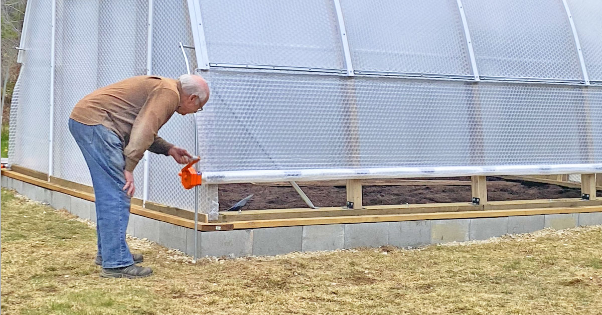 A customer rolls up the side vents of his new Solawrap 4-20 Argenta Greenhouse in Hills BC. 